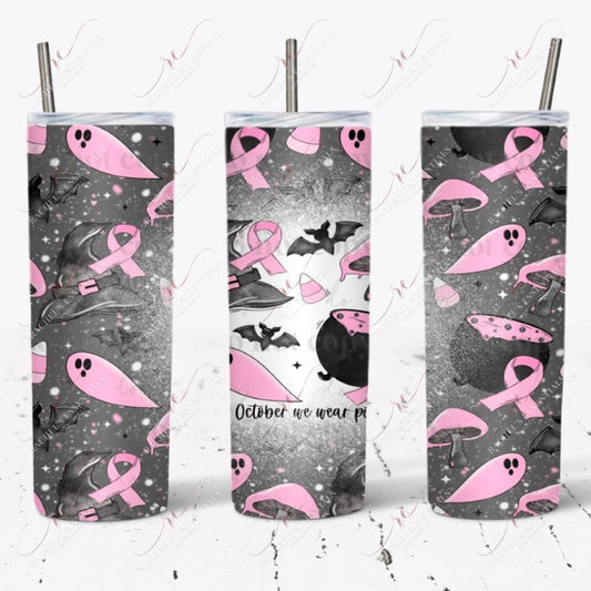 seamless halloween design. Dark grey background with white and pink dots and stars. The foreground has a black cauldron with pink potion bubbling out. Black bats and witches hats, pink candy corns, pink ghost, pink mushrooms, and a pink breast cancer awareness ribbon. The words In October we wear pink are written on 1 side of the design with a splattered bleach effect.