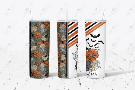 Salem, MA. Tumbler with straw featuring dark grey, orange and yellow flowers. The remaining tumbler features a spider and spiderweb, grey and black stripes with flowers and bats. The words Salem, MA is written at the bottom. .