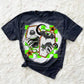 Bleached dark heather grey shirt featuring a halloween design. The design is 2 orange coffins with skeleton hands coming out of the side holding a bottle of poison and a black cat. A black bat, spider web and crescent moon are also featured throughout the design. Neon green checkered squares are in the background of the design.