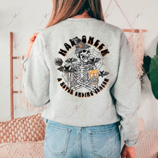 Back of model wearing a light grey sweatshirt. A Halloween design featuring the words Halloween A Never Ending Season and a skeleton holding a witches broom and eating popcorn is in the center of the design. A witches hat is on top of the skeleton's head and spider webs and bats are in the background of the design