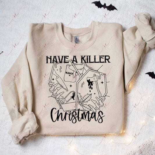 sand color sweatshirt featuring a spooky Christmas design. The design has a spiderweb in the background with 2 coffins in front with skeleton hands coming out of it. Bleach bottles, knives, chainsaws, bloody axes and holly berries are inside the coffin. The wording have a killer Christmas is featured above and below the design. 