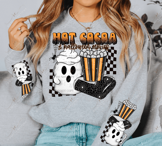 Model wearing a grey crewneck sweatshirt. 2 designs on each sleeve featuring a white ghost mug with whip cream, a spider blanket, and a black and orange bucket with popcorn. The same image is on the center of the sweatshirt with the words hot cocoa and halloween movies written at the top. A spider is dangling down from the words in his web