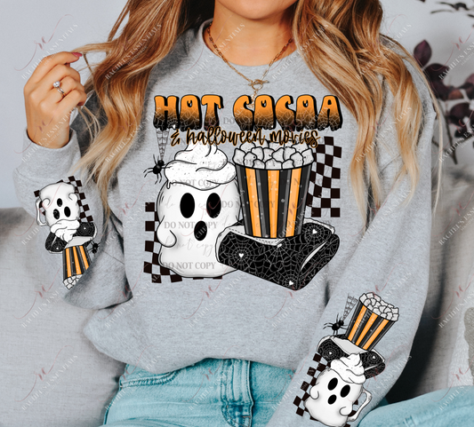 Model wearing a grey crewneck sweatshirt. 2 designs on each sleeve featuring a white ghost mug with whip cream, a spider blanket, and a black and orange bucket with popcorn. The same image is on the center of the sweatshirt with the words hot cocoa and halloween movies written at the top. A spider is dangling down from the words in his web