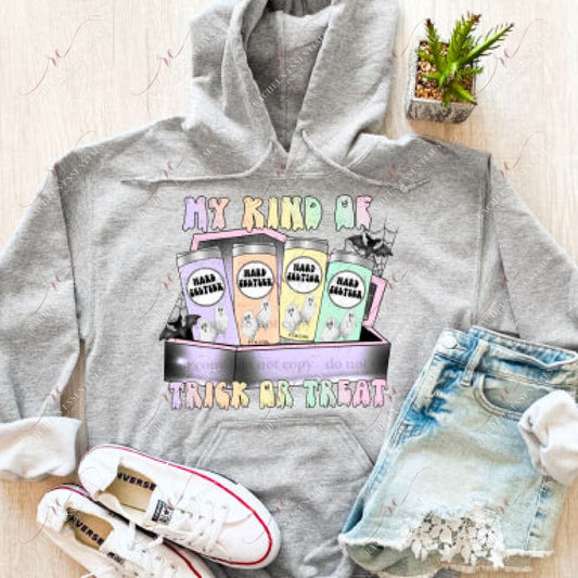 A grey hoodie with a halloween design featuring 4 cans of hard seltzer in pastel colors with ghosts on the cans. The cans are sitting inside a coffin with spider webs and bats flying out. The words my kind of trick or treat are written in pastel colors above and below the coffin