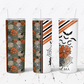 Salem, MA. Tumbler with straw featuring dark grey, orange and yellow flowers. The remaining tumbler features a spider and spiderweb, grey and black stripes with flowers and bats. The words Salem, MA is written at the bottom. . 