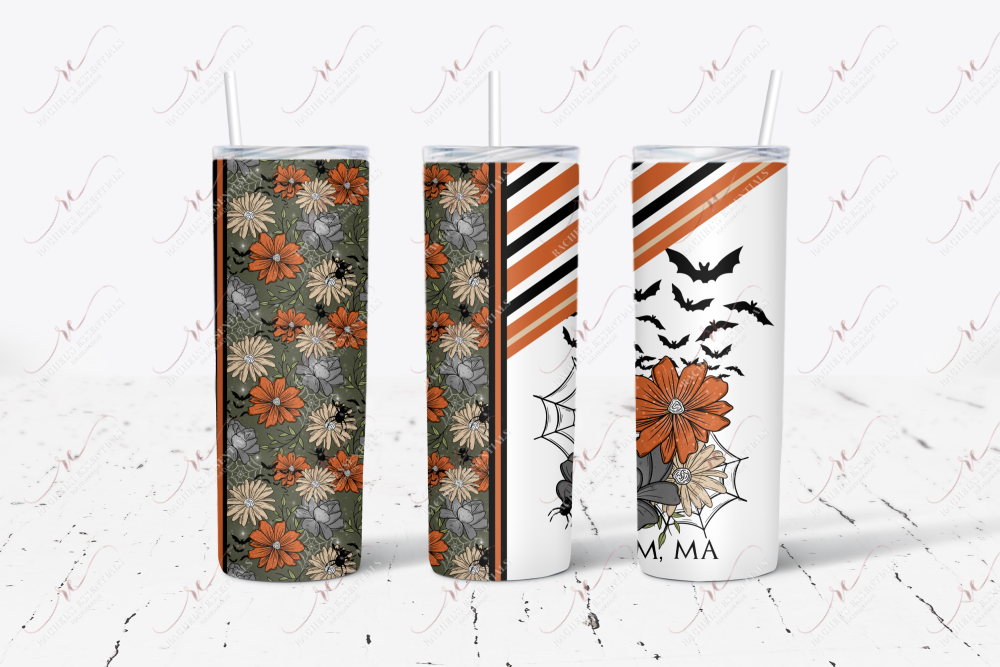 Salem, MA. Tumbler with straw featuring dark grey, orange and yellow flowers. The remaining tumbler features a spider and spiderweb, grey and black stripes with flowers and bats. The words Salem, MA is written at the bottom. . 